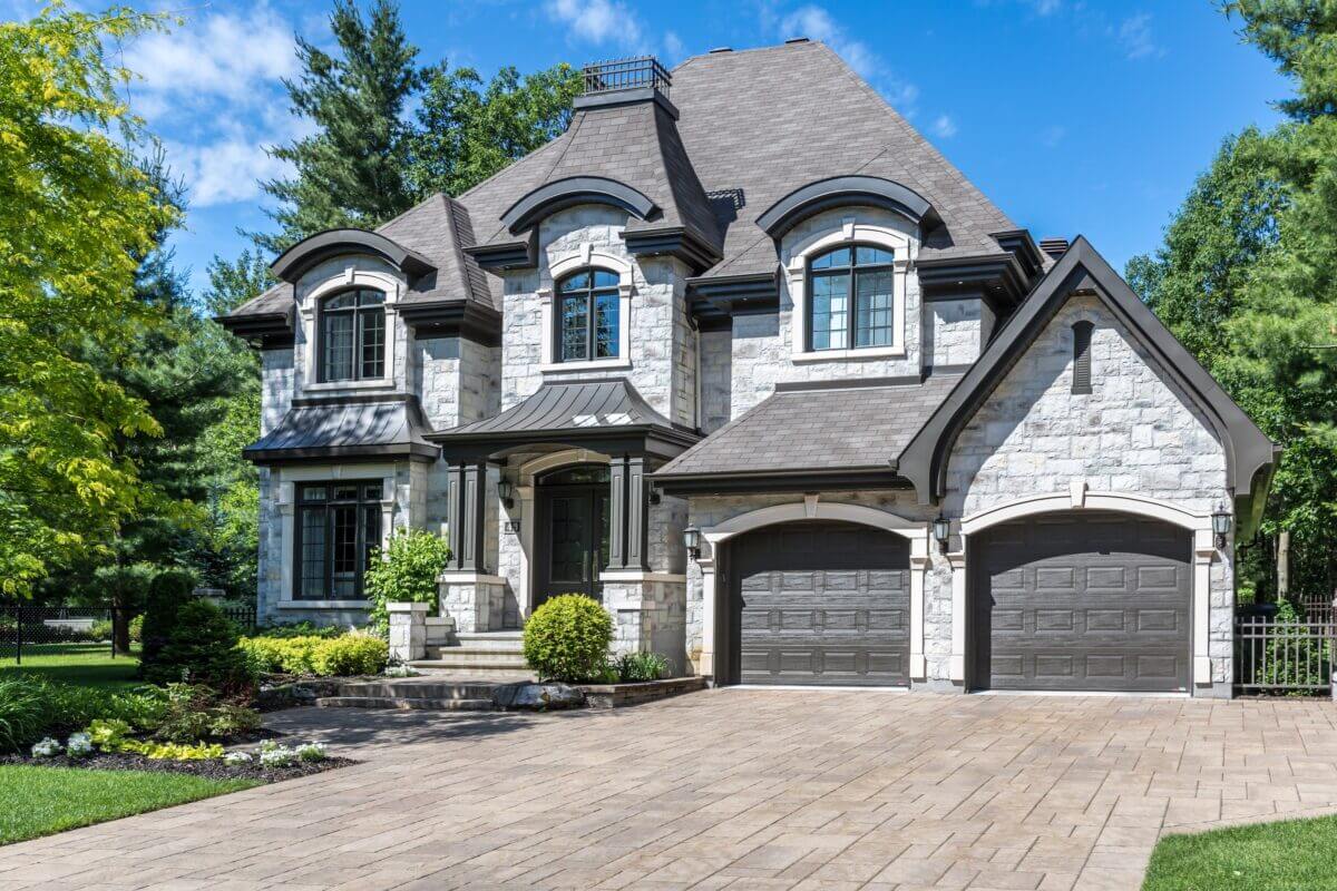 luxury stone house with paver driveway and two car garage