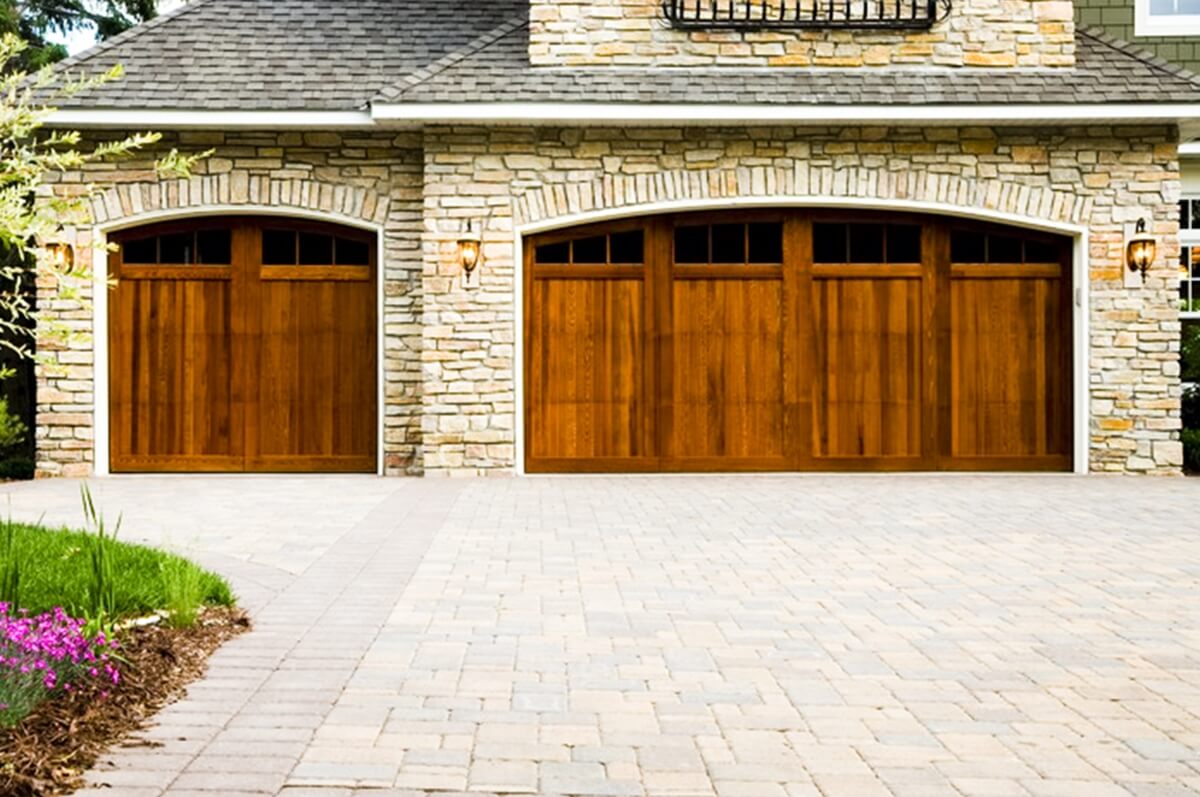 paver driveway with wooden garage door on stone house