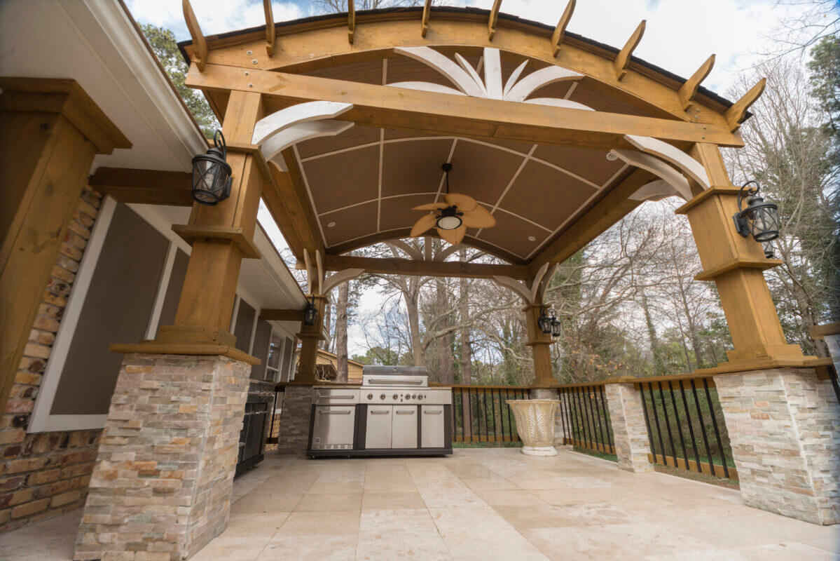 pergola with ceiling fan over stone patio with outdoor stainless steel grill
