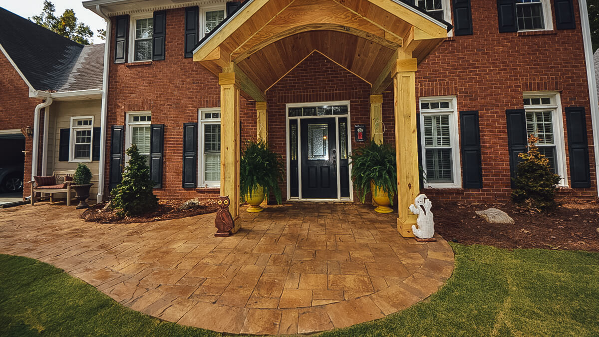 front door of brick house with wooden portico and hardscape walkway