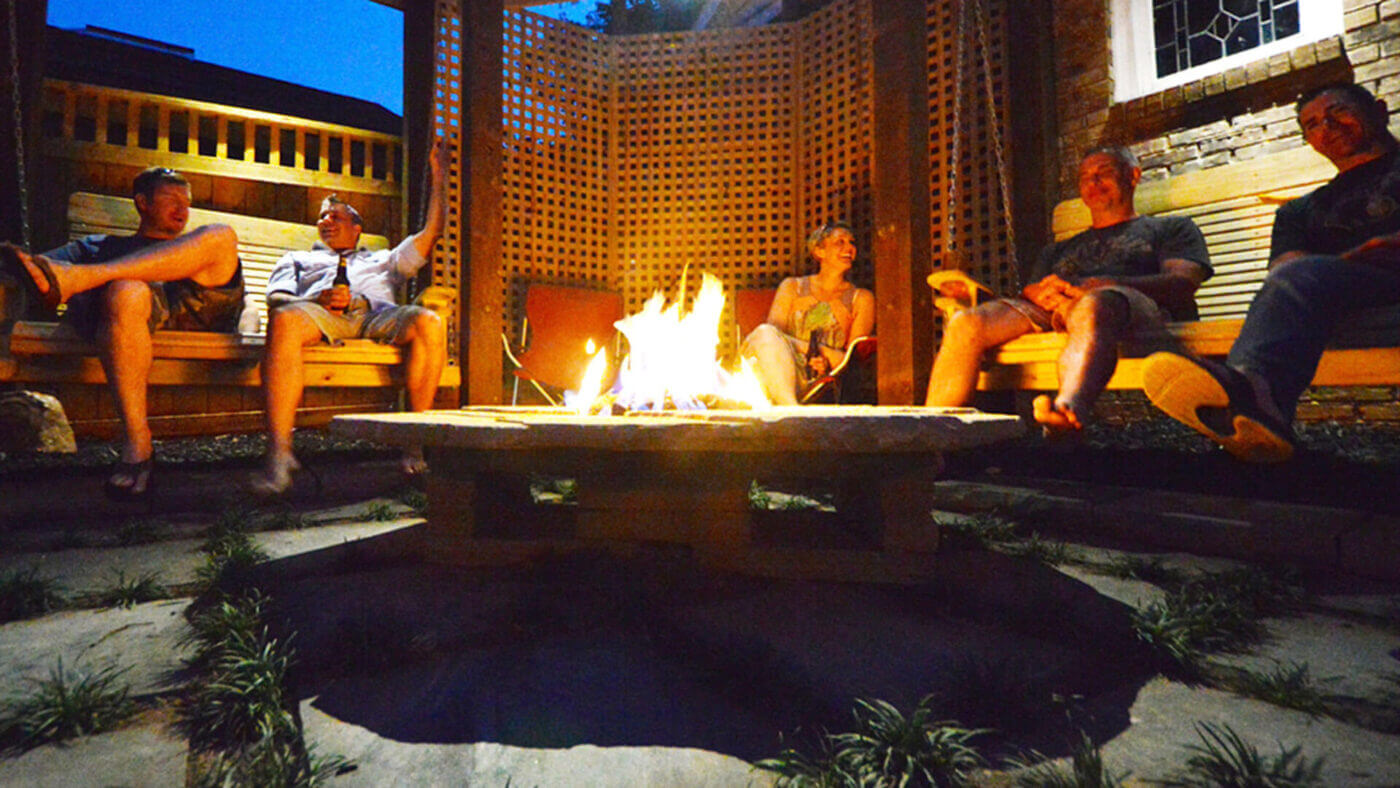 people sitting around outdoor living space with fire pit and wooden swings
