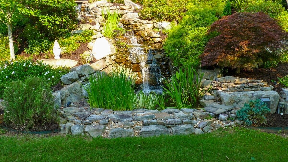 backyard stone waterfall with colorful landscaping