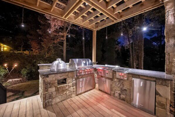 outdoor kitchen and grill on wood deck with pergola and outdoor lighting