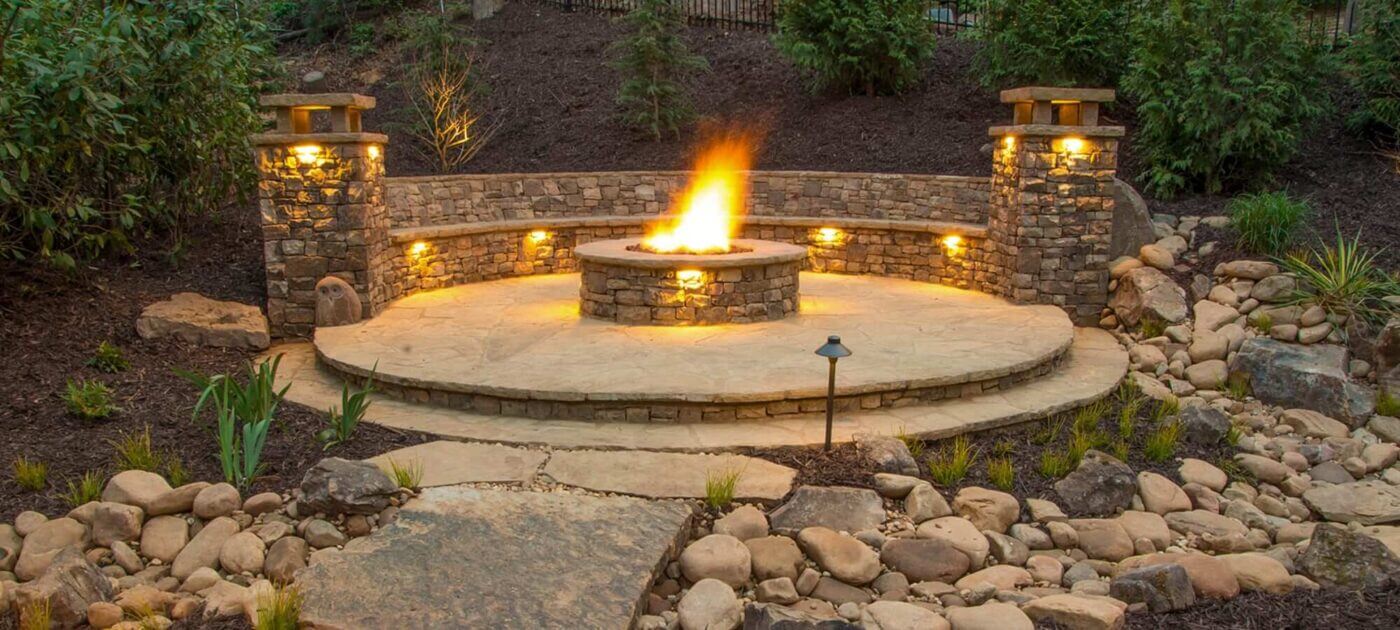 outdoor fire feature on hardscape outdoor living space with outdoor pathway and surface lighting
