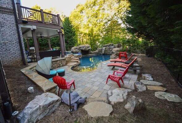 poolside hardscaping with red outdoor furniture and backyard deck and patio