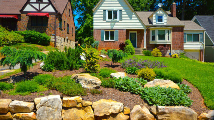 frontyard landscape of brick house with colorful plants and grass yard