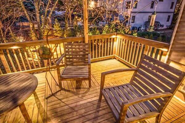 backyard living space wooden deck with surface lights and wooden chairs around table