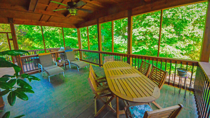 screened-in backyard porch with lounge chairs and wooden outdoor dining area